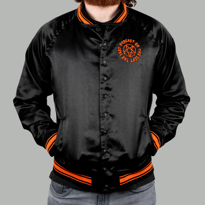 Man in black satin jacket with orange pentagram on left chest with text "THE LAST PODCAST ON THE LEFT"