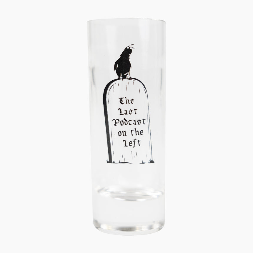 Shot glass with crow on top of gravestone with text "The Last Podcast on the Left"