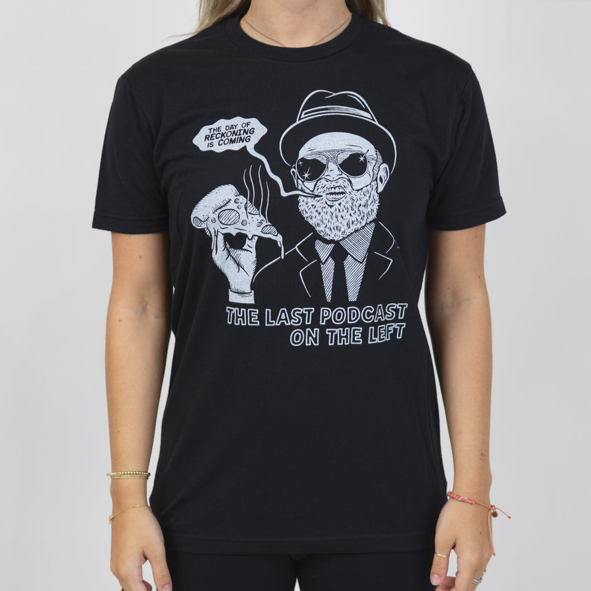 Woman in black shirt withgraphic of man in suit and hat holding pizza with speech bubble "THE DAY OF RECKONING IS COMING" and text below "THE LAST PODCAST ON THE LEFT"
