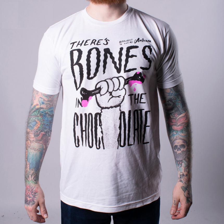 White tee with graphic of hand holding bone with text "THERE'S BONES IN THE CHOCOLATE"
