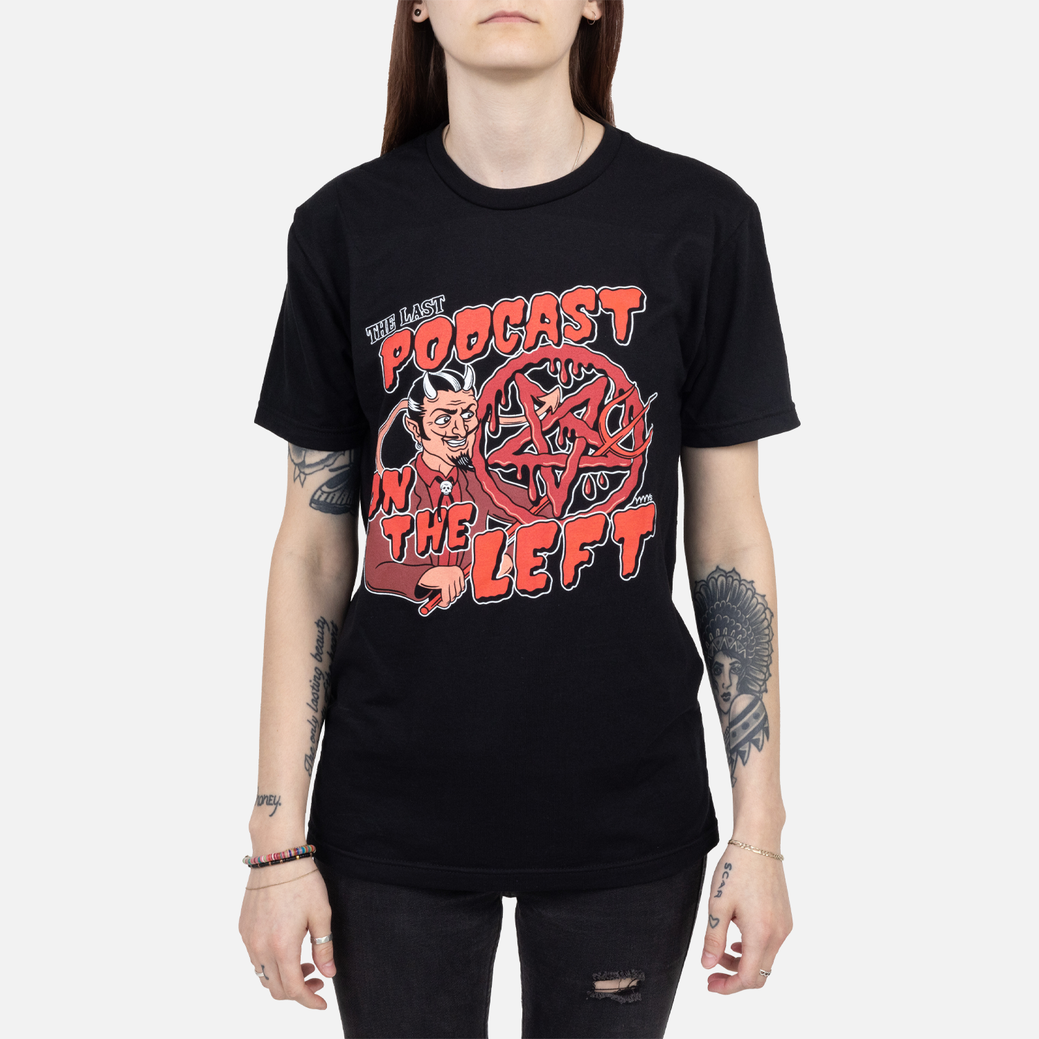 Black tee with graphic of devil and pentagram with text "THE LAST PODCAST ON THE LEFT" on female model