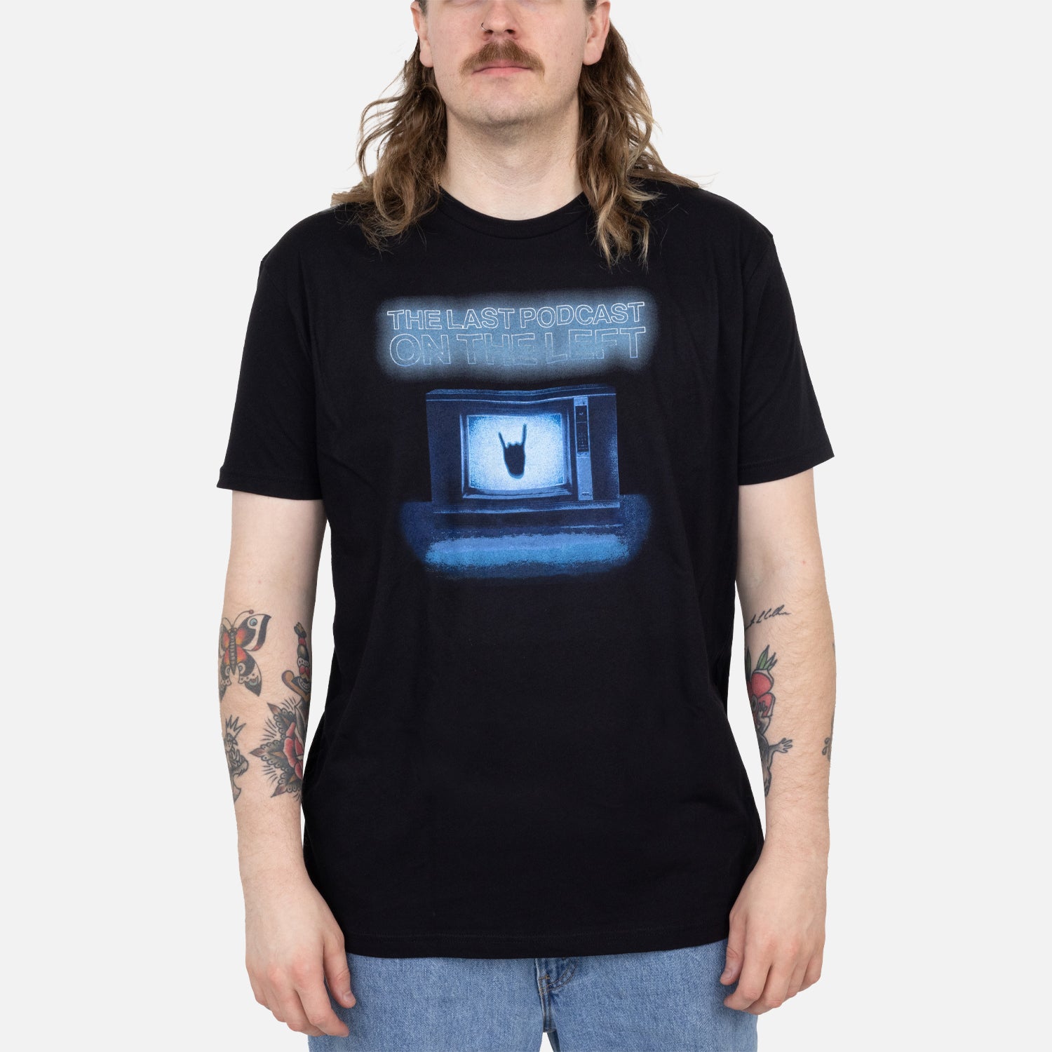 Male model wearing black tee with graphic of tv with hand making horns with text "THE LAST PODCAST ON THE LEFT"