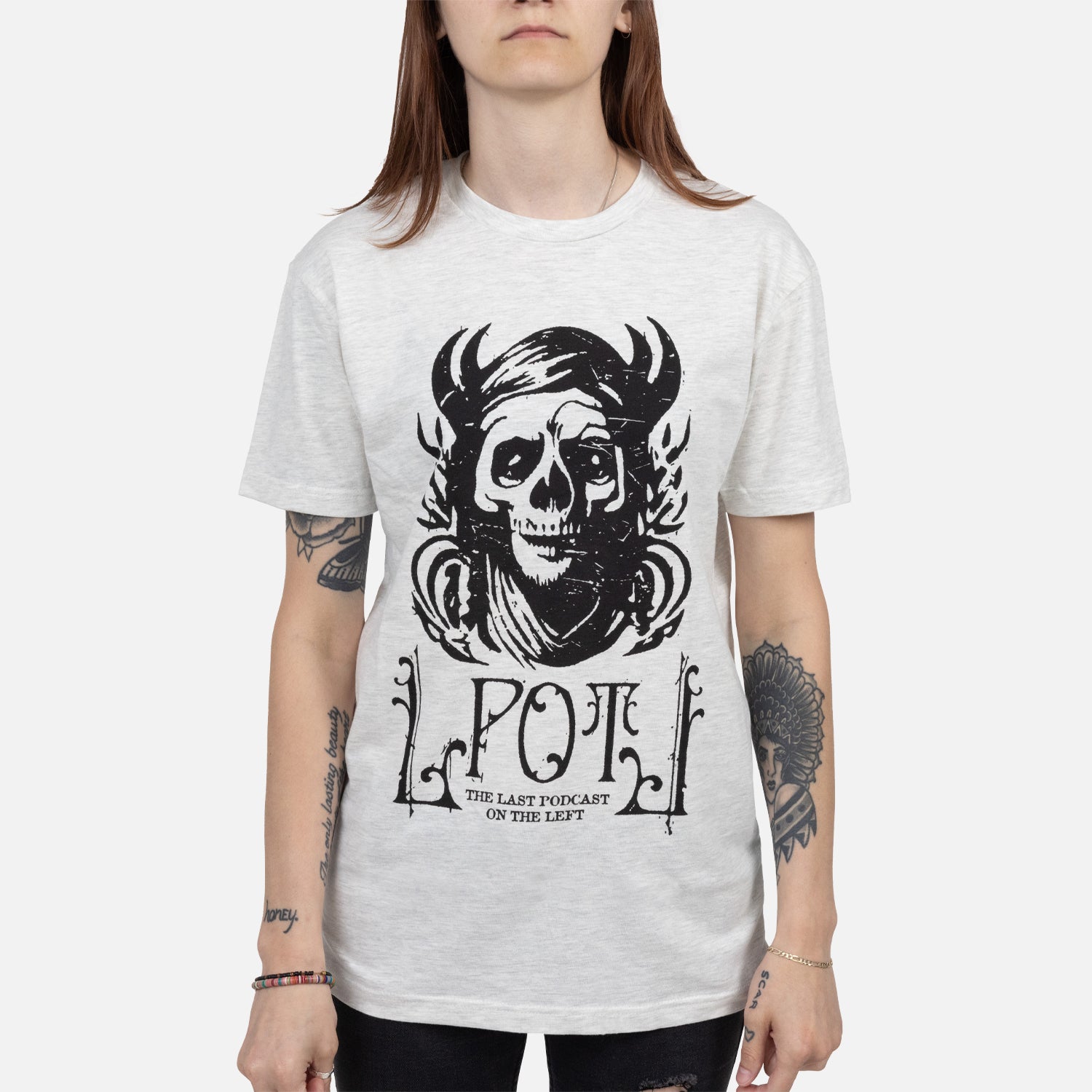 Female model wearing Oatmeal tee with graphic of pagan skull with text "LPOTL THE LAST PODCAST ON THE LEFT"