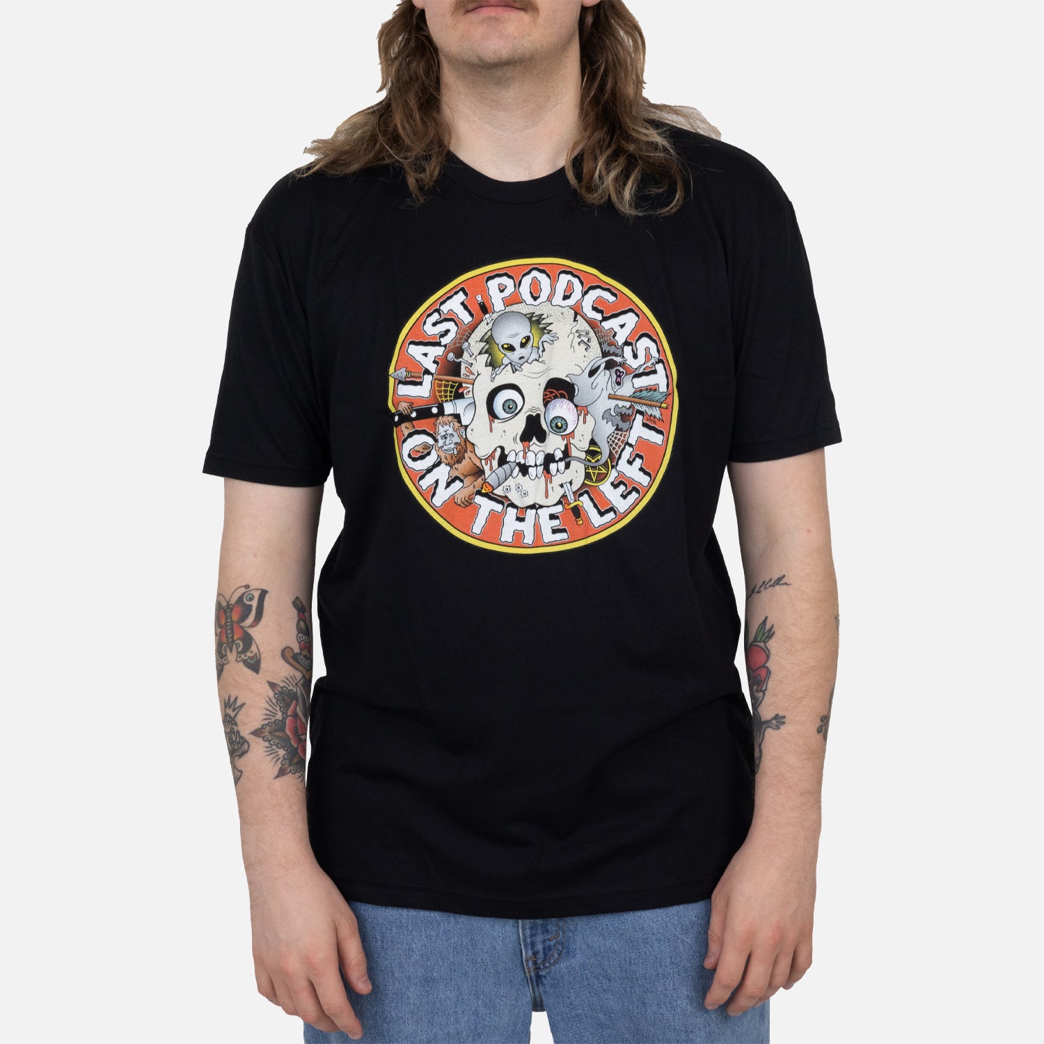 Male model wearing black tee with graphic of skull with orange background surrounded by white text "LAST PODCAST ON THE LEFT"