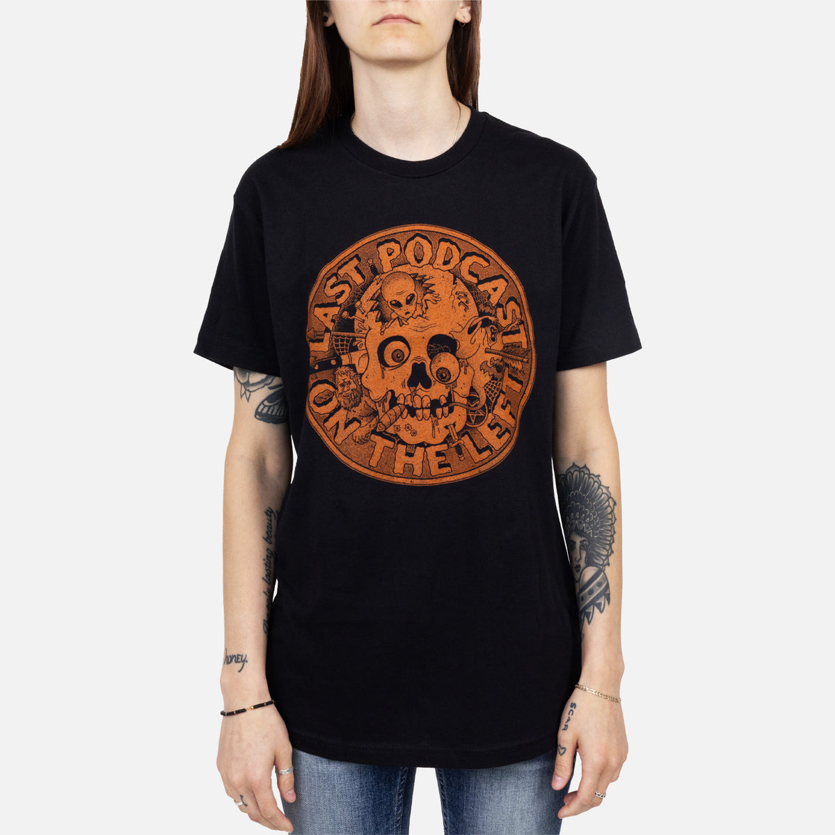 female model wearing Black tee with orange skull graphic with text "LAST PODCAST ON THE LEFT"