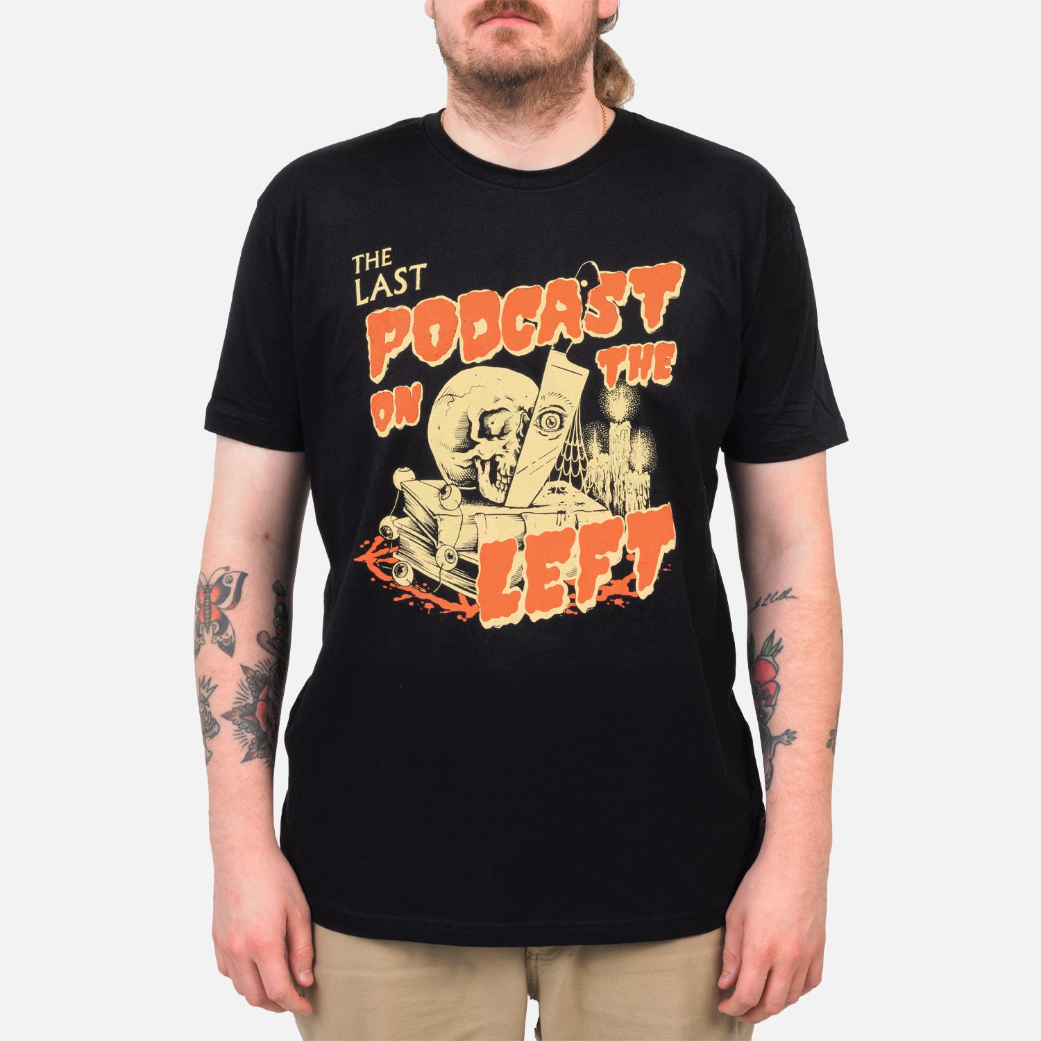 black tee on male model with THE LAST PODCAST ON THE LEFT logo featuring skull knife and books and candle graphic