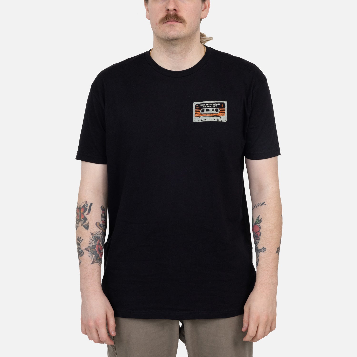 Black shirt on male model with cassette graphic on left chest with text "THE LAST PODCAST ON THE LEFT"