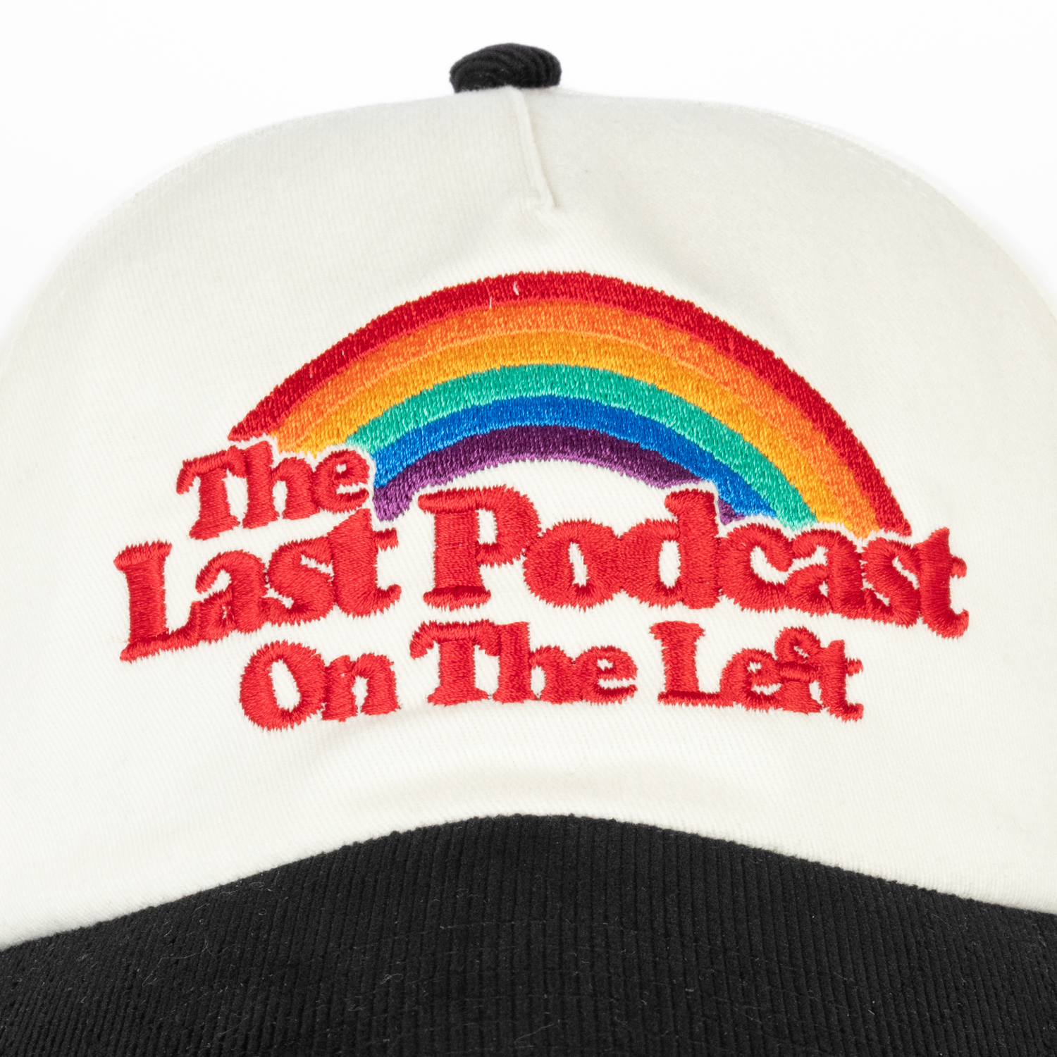 Closeup of front of Cream and black hat with rainbow on front with text "The Last Podcast On The Left"