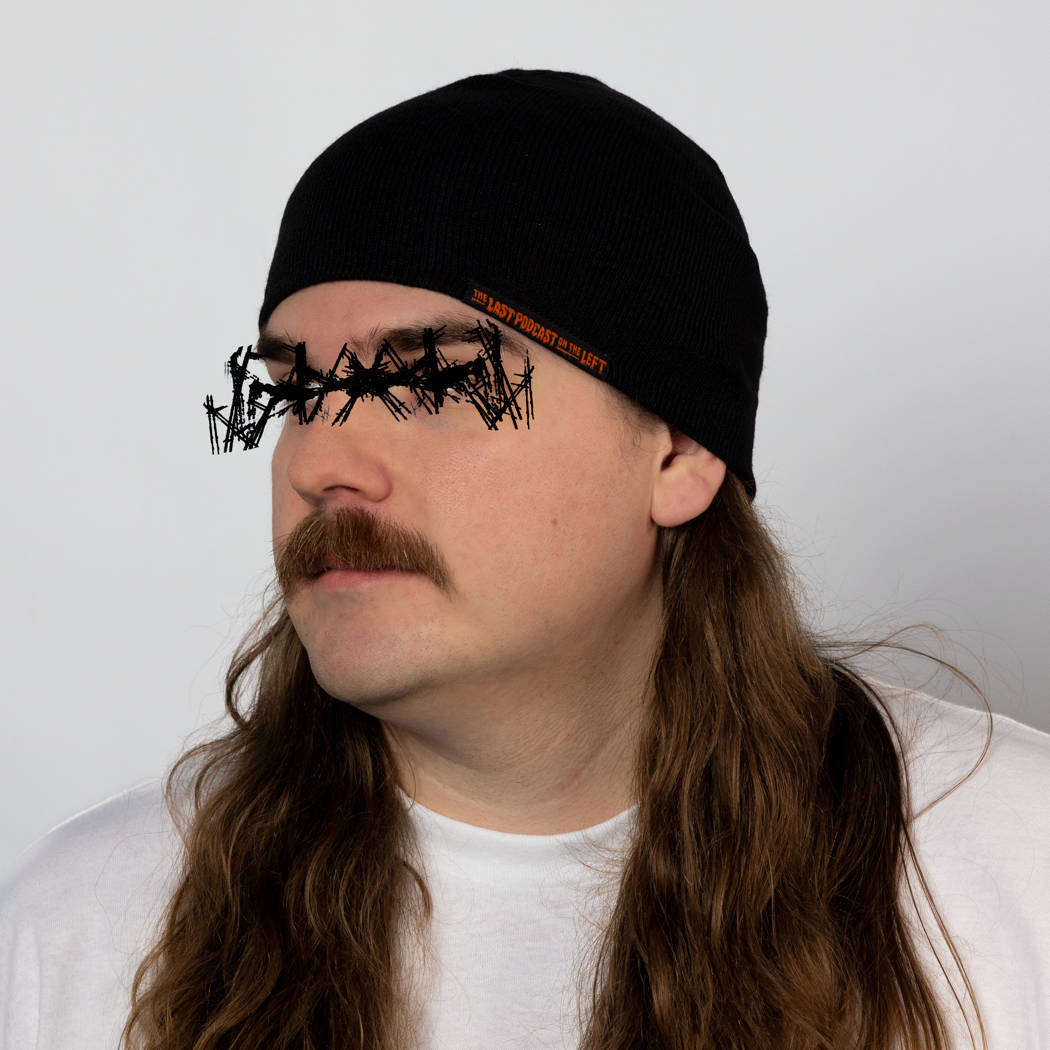 Person wearing a black beanie with orange text "THE LAST PODCAST ON THE LEFT"