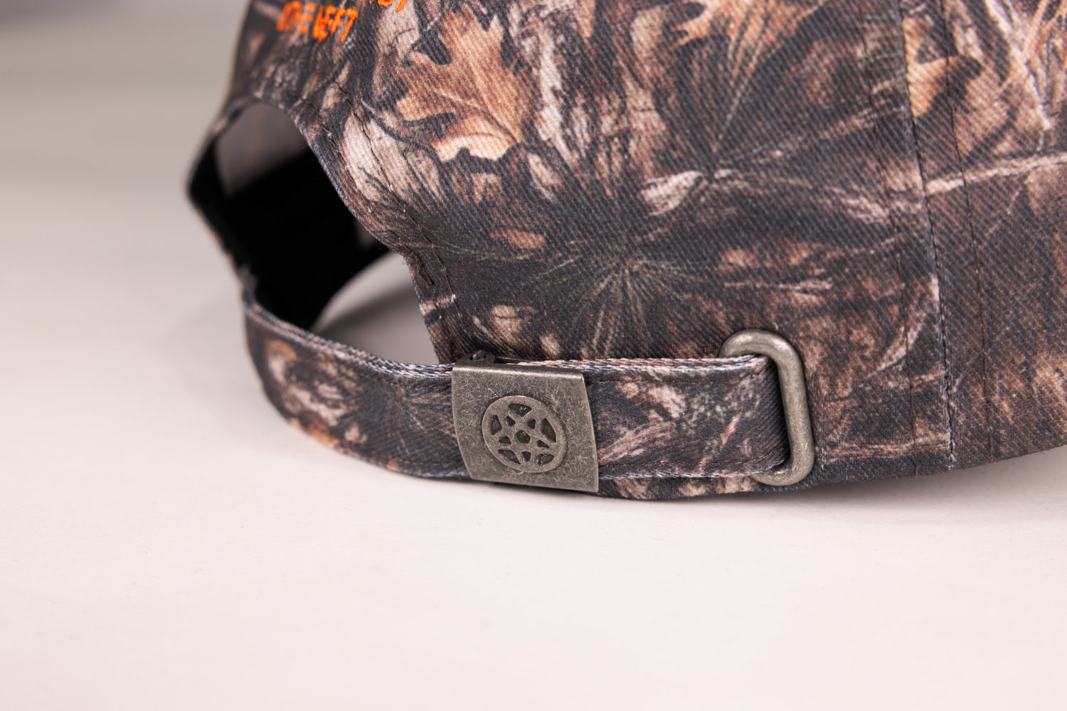 closeup of adjustable strap on rear of camo hat with Pentagram on clasp