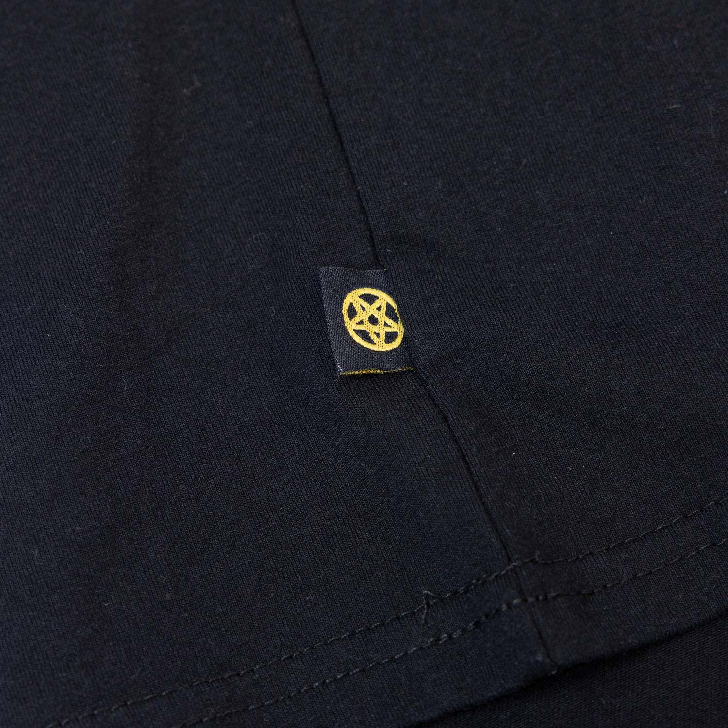 closeup of yellow pentagram woven label on here's Henry tee