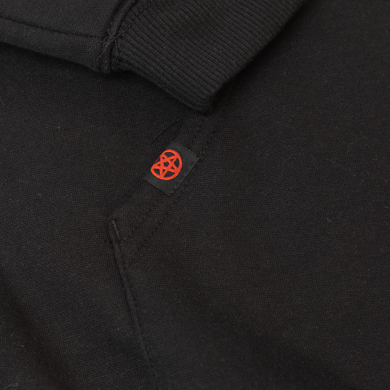 closeup of orange pentagram woven lable on black hoodie