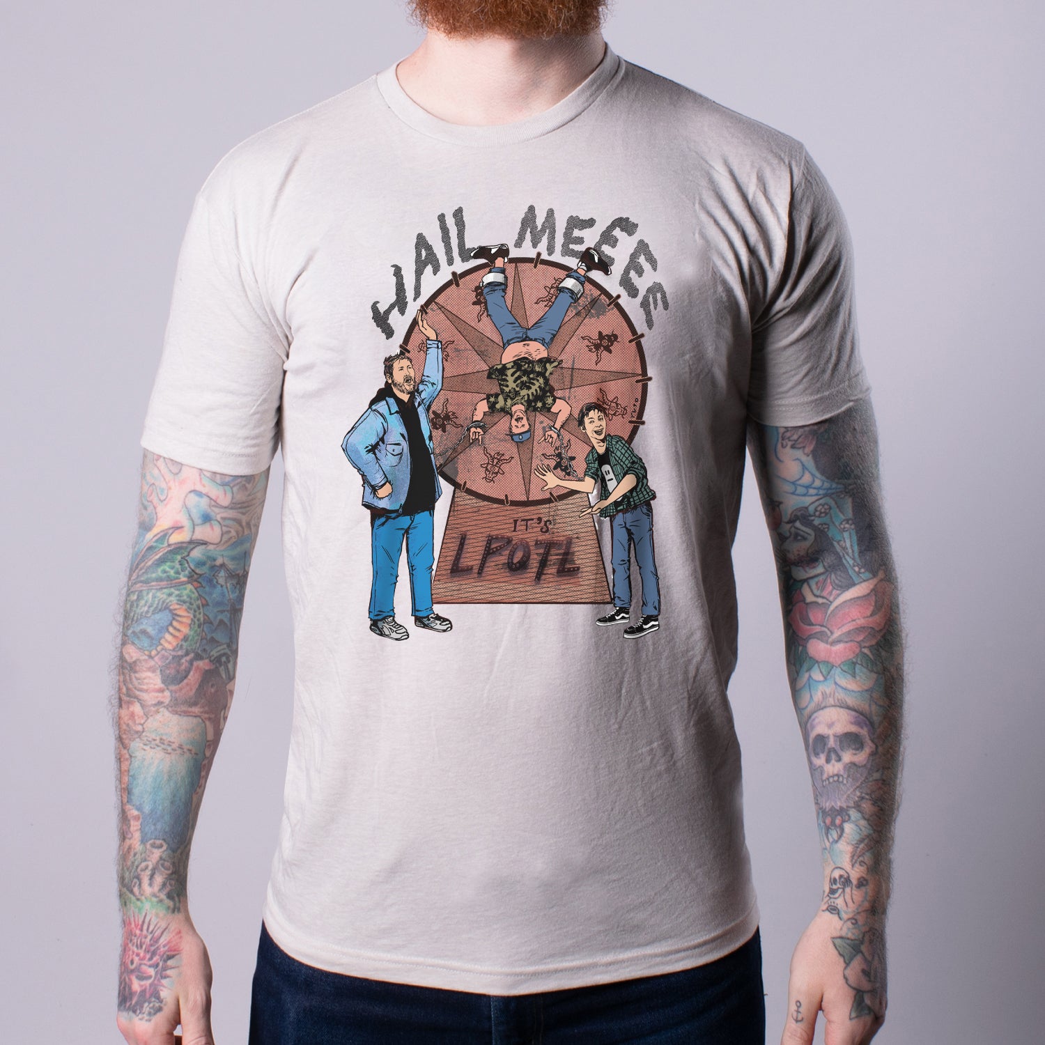 Man in Sand Heather shirt with graphic of Man on spinning wheel and HAIL MEEEE IT'S LPOTL text