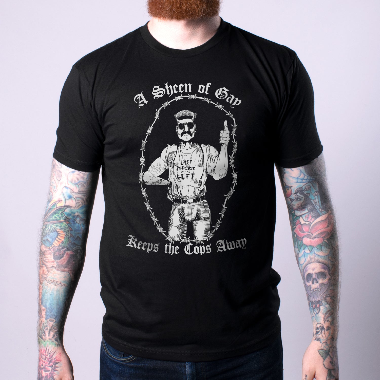 Man in black shirt with graphic of man surrounded by barbed wire with text "A Sheen of Gay Keeps the Cops Away"