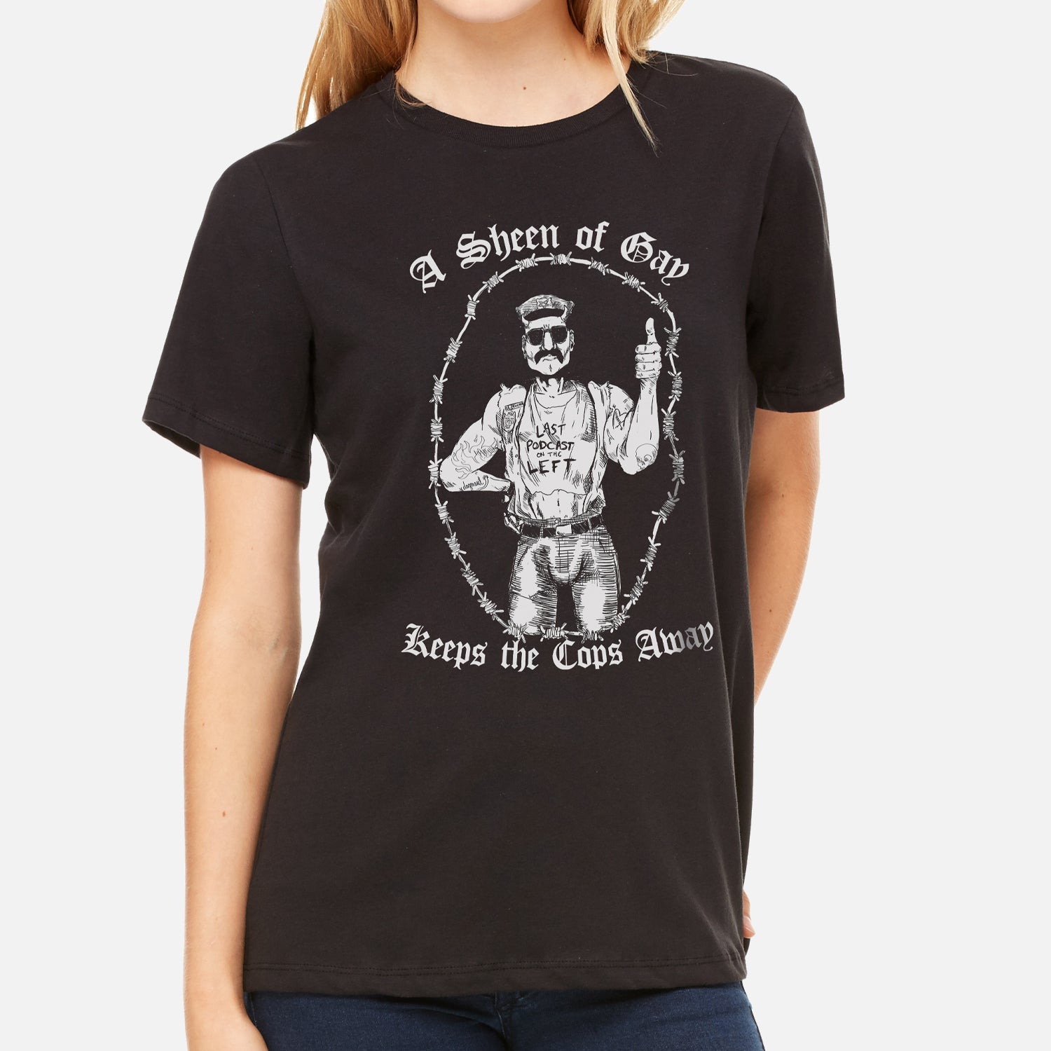 woman in black shirt with graphic of man surrounded by barbed wire with text "A Sheen of Gay Keeps the Cops Away"