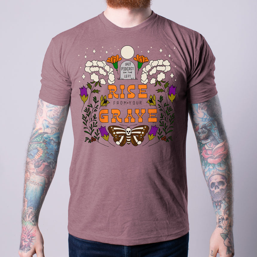 photo of male model wearing flowers for your grave tee in heather mauve. last podcast on the left on gravestone at top. rise from your grave in orange below. moth with skull body below