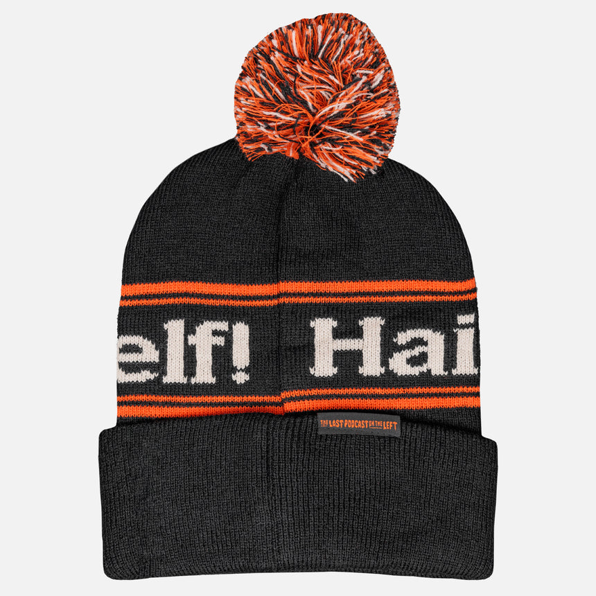 photo of hail yourself pom beanie. black with orange stripes and orange and black with orange and black pom on top. hail yourself around top between orange bars. 