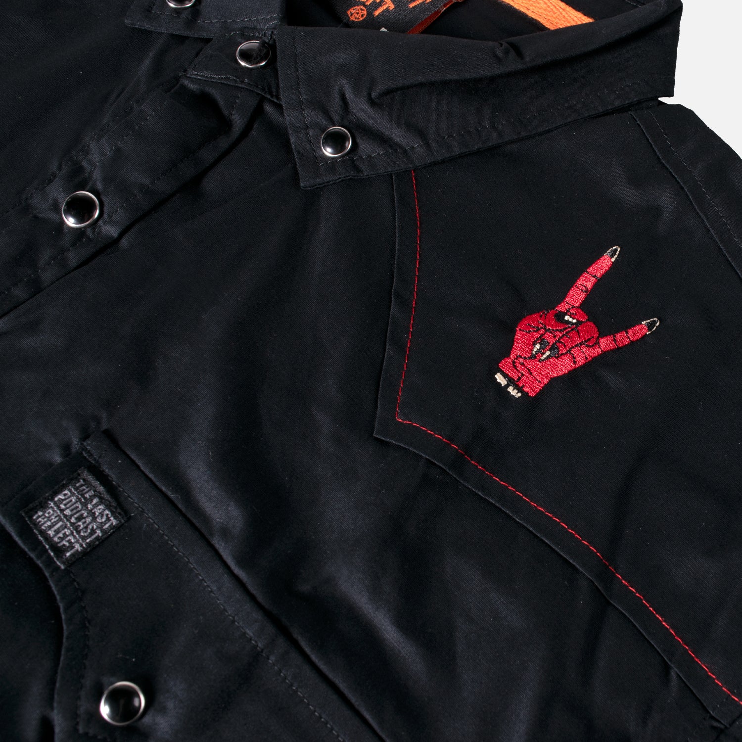 closeup of shoulder on black longsleeve buttondown showing red hand on shoulder making horn sign