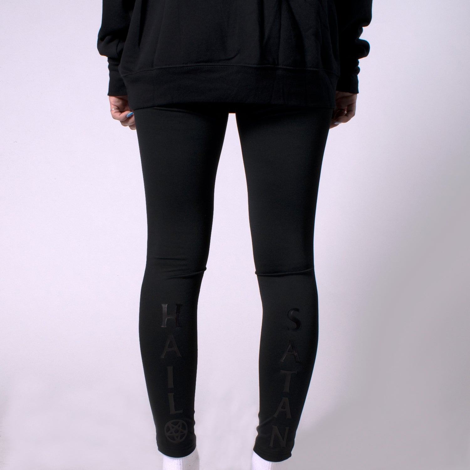 back view of woman in mauled compression leggings with hail satan on legs