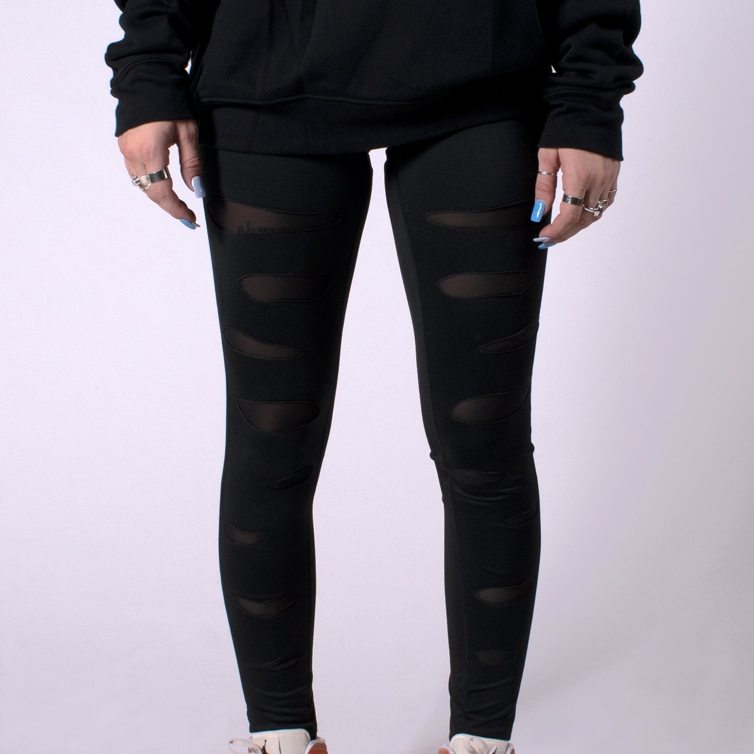 closeup front view of woman in ripped black mauled compression leggings