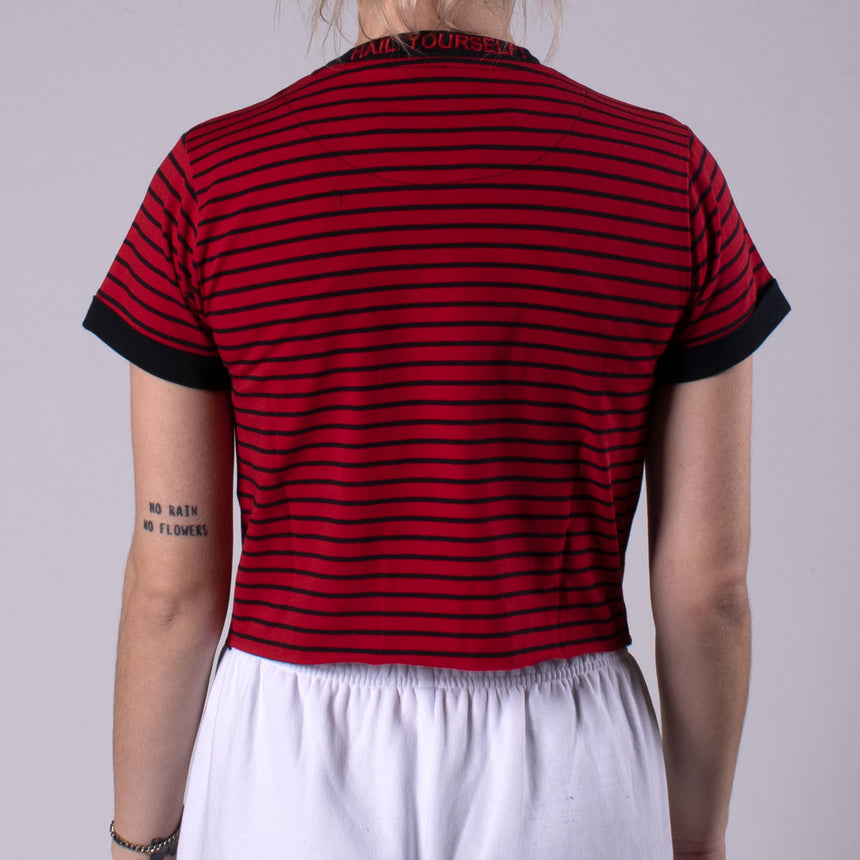 Woman in crimson shirt with black stripes with pocket on chest with LPOTL pentagram graphic