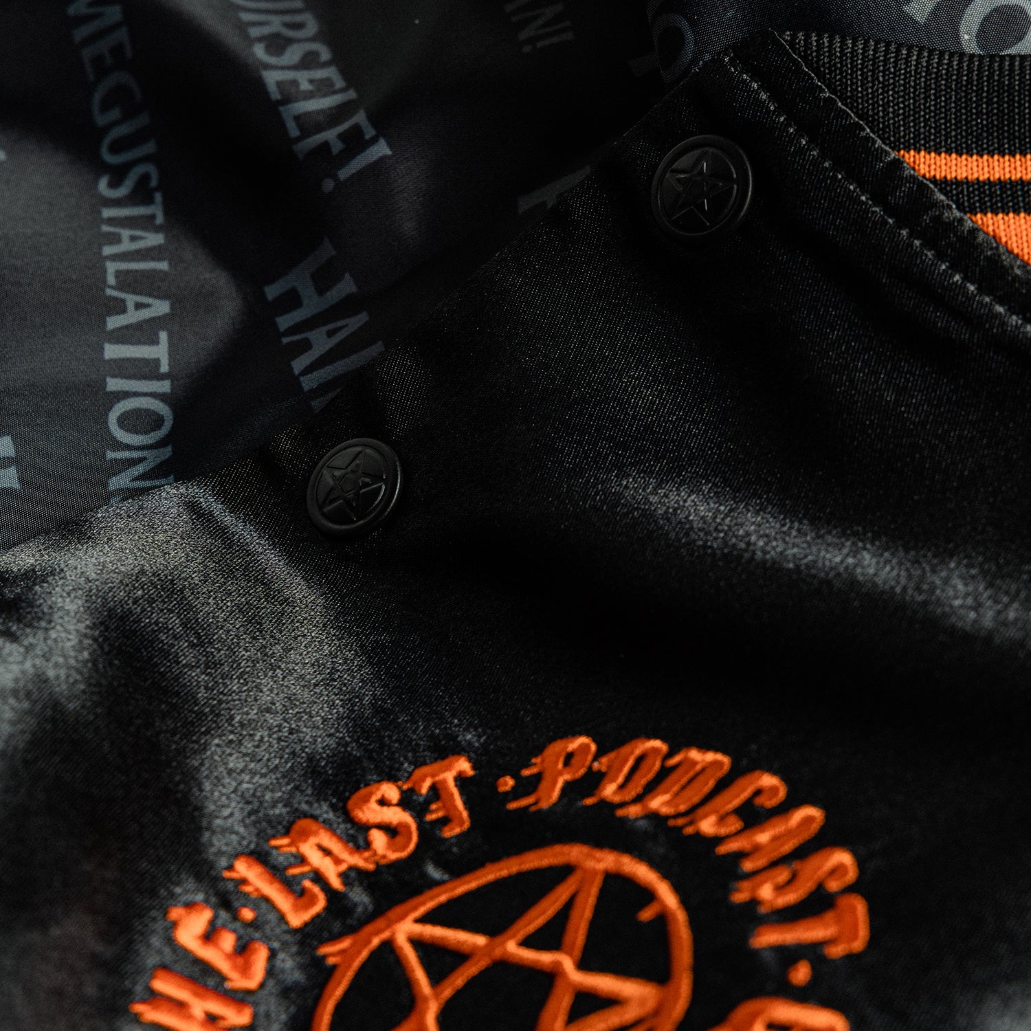 closeup of front left of black satin jacket showing orange pentagram with text "THE LAST PODCAST ON THE LEFT" and closeup of interior with various text "HAIL SATAN! HAIL ME! HAIL GEIN! MEGUSTALATIONS HAIL YOURSELF!"