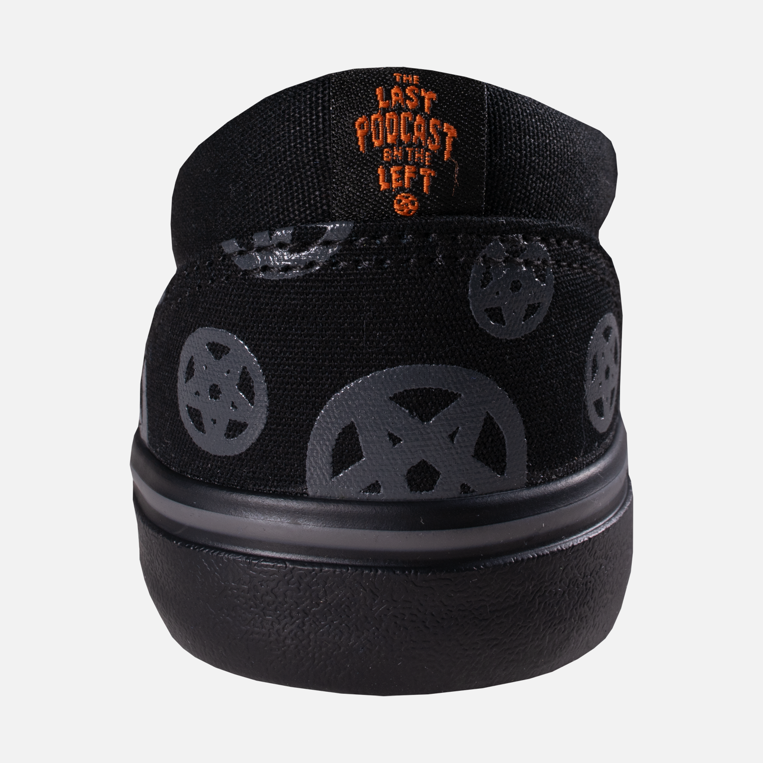 back of black slip on shoe with orange text on label the last podcast on the left
