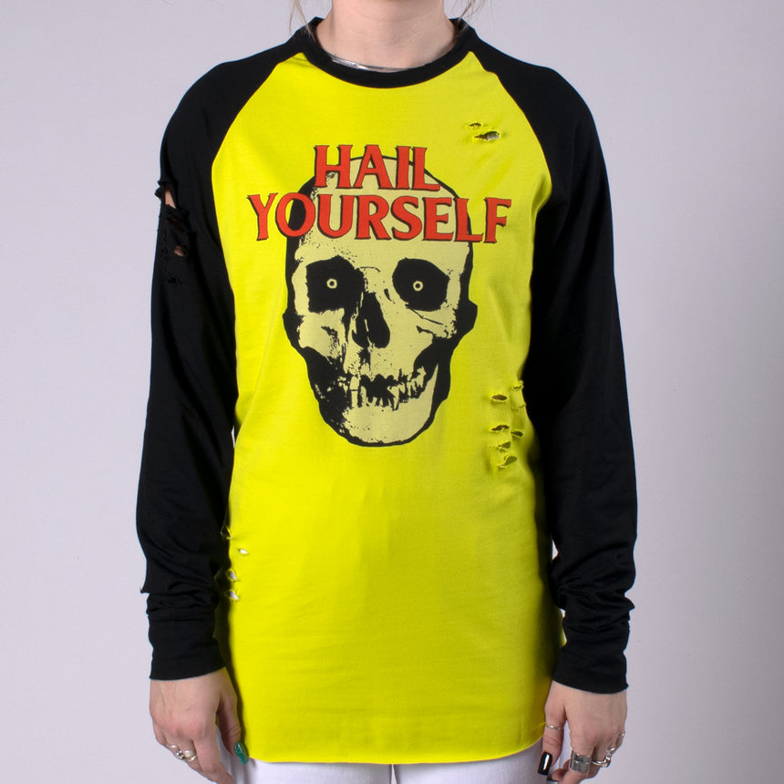 Man in Longsleeve Raw edge shirt with Black sleeves and acid yellow torso with skull graphic on front and dark red HAIL YOURSELF TEXT