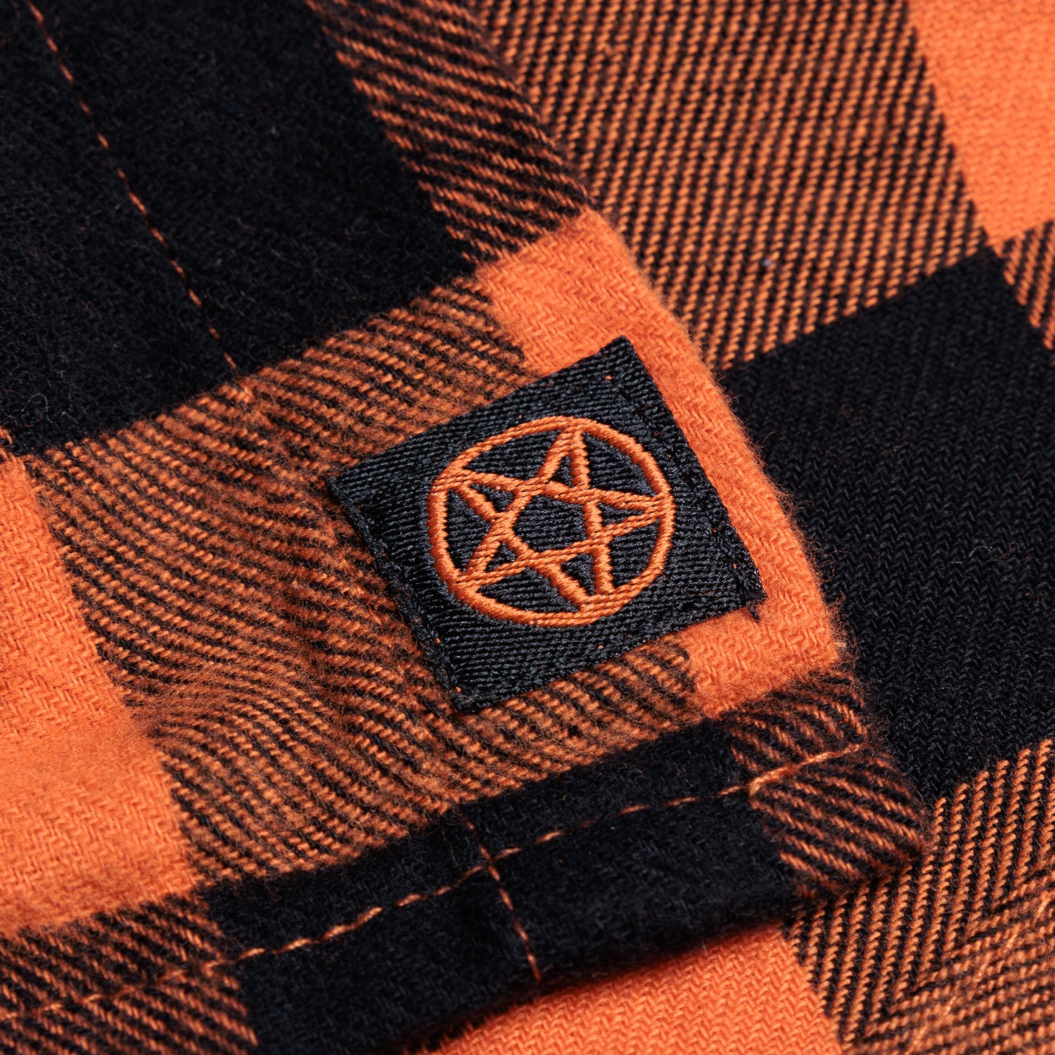 closeup of black label on orange/black flannel with orange pentagram