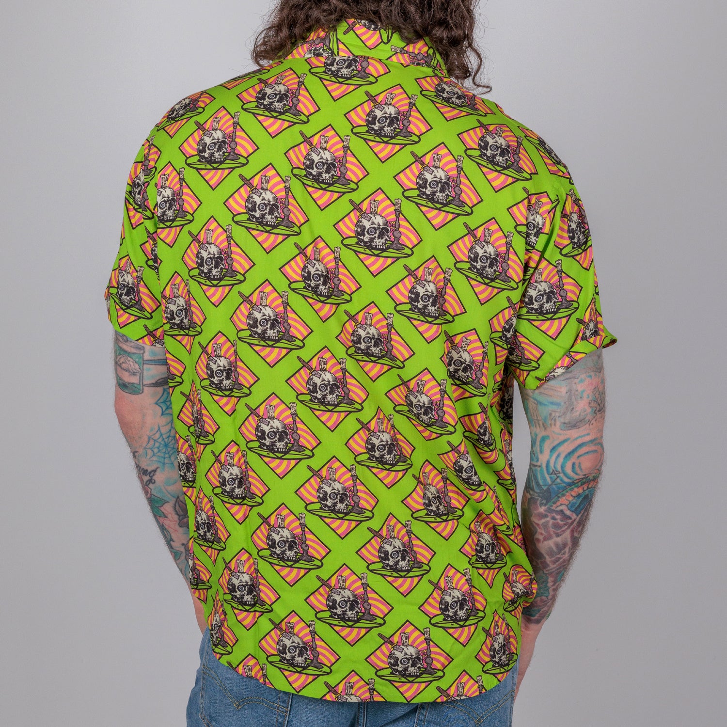 rear view photo of male model wearing occult altar short sleeve buttondown. acid green background with skull on plate on orange background.