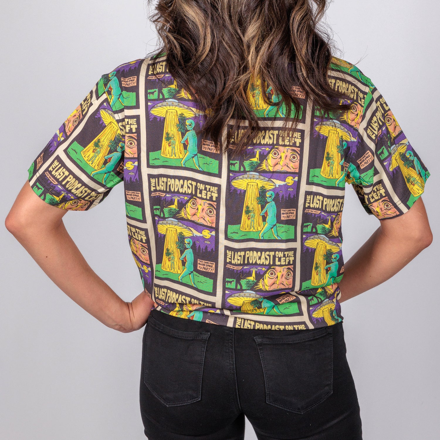 rear photo of female model wearing party time short sleeve button down. comic book background with alien and spaceship