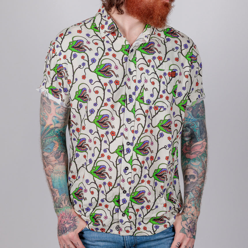 photo of female model wearing man-eating plant short sleeve buttondown in bone color. pattern of man eating plant