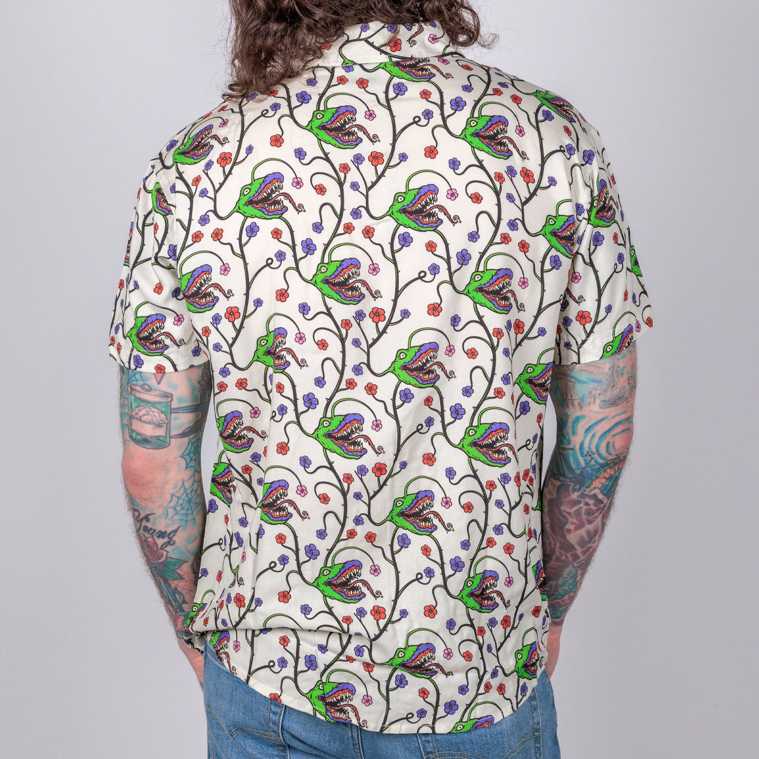 rear view photo of male model wearing man-eating plant short sleeve buttondown in bone color. pattern of man eating plante