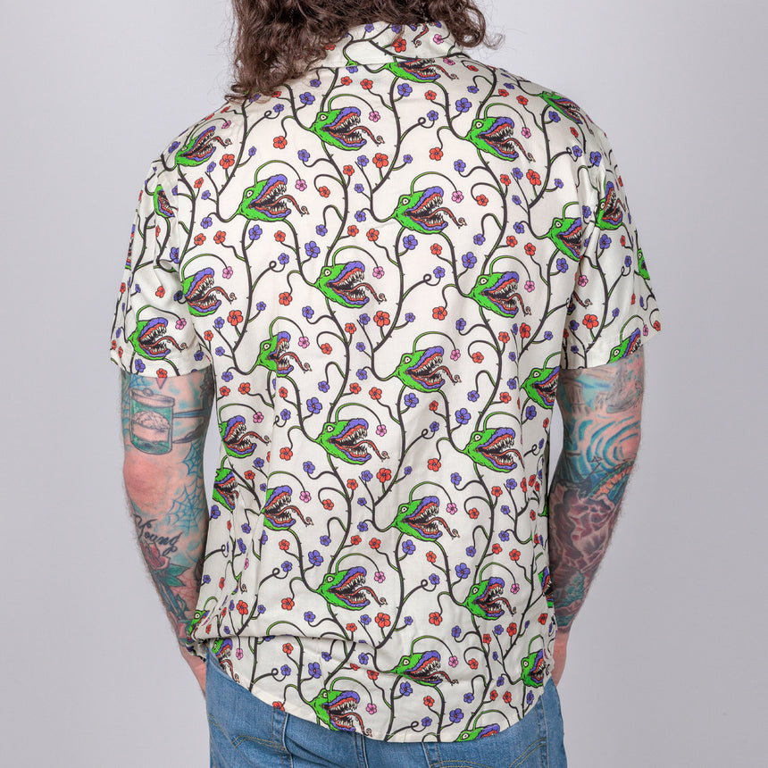 photo of male model wearing man-eating plant short sleeve buttondown in bone color. pattern of man eating plant.