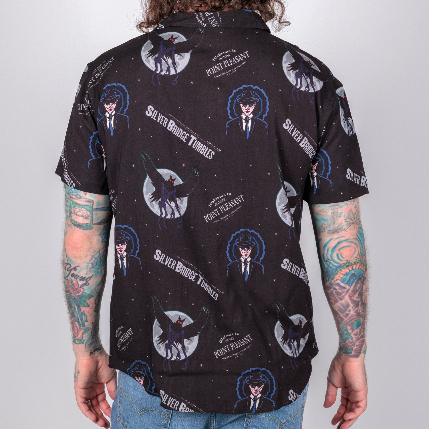 rear photo of male model wearing point pleasant short sleeve button down, black background with man in suit an winged demon pattern