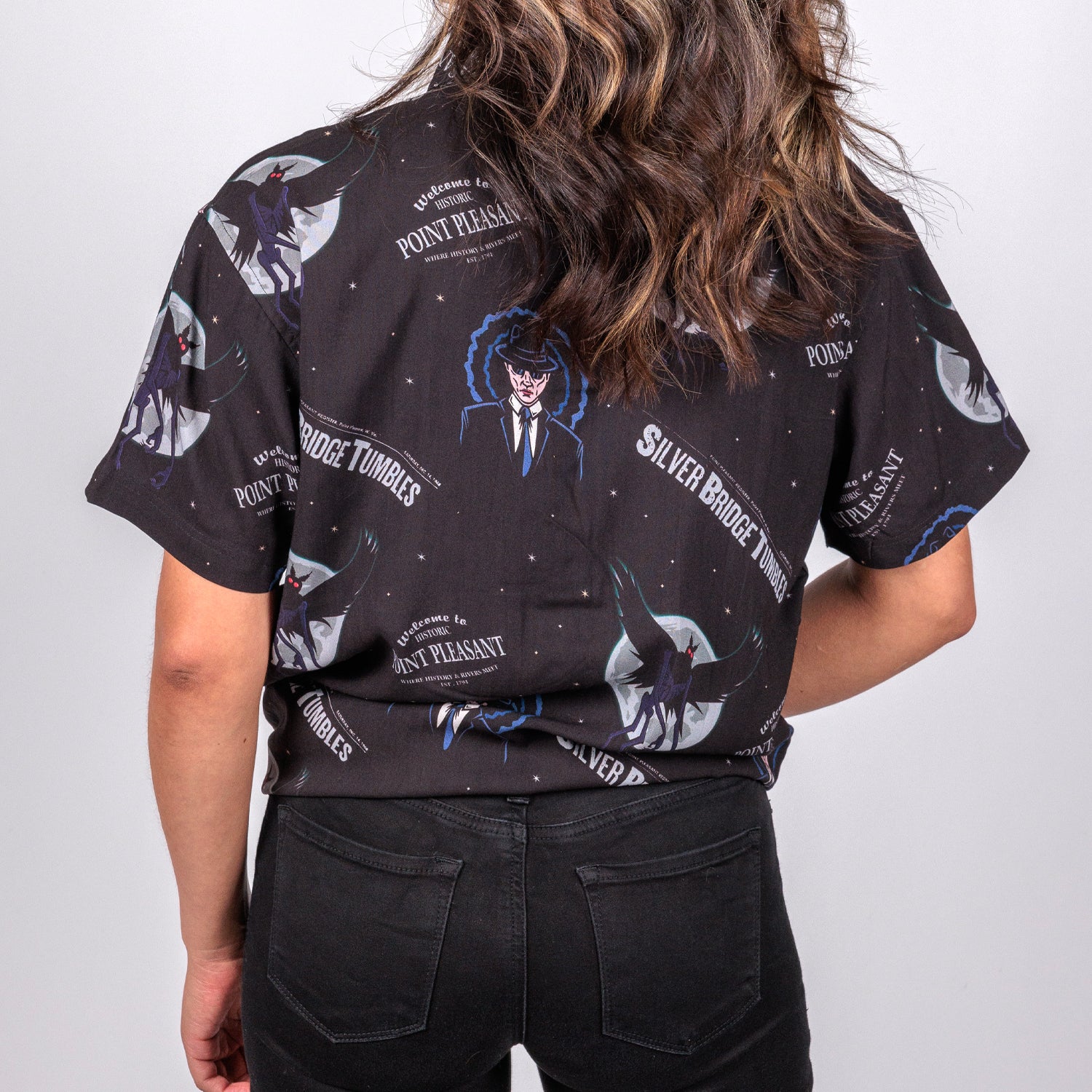 rear view photo of female model wearing point pleasant short sleeve button down, black background with man in suit an winged demon pattern