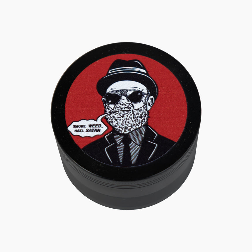 4 part black grinder with graphic on top of man in suit and hat with text bubble "Smoke weed hail satan" with red background