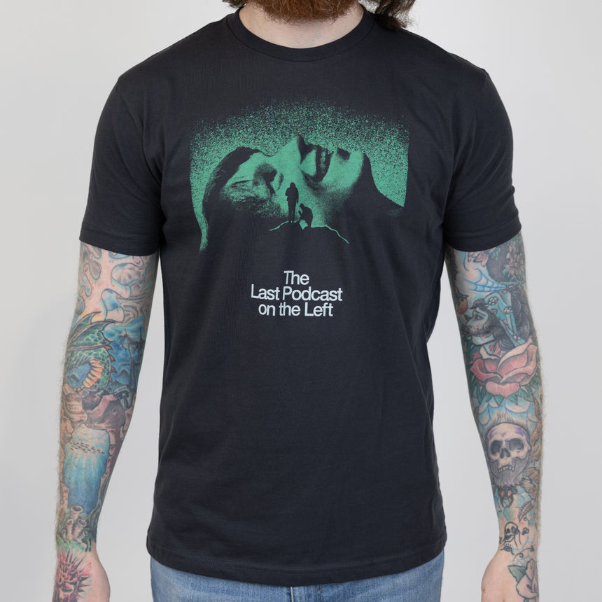 man in black shirt with green graphic on front of man laying down behind silhouette of 2 people on summit of hill with white text below "The Last Podcast on the Left"