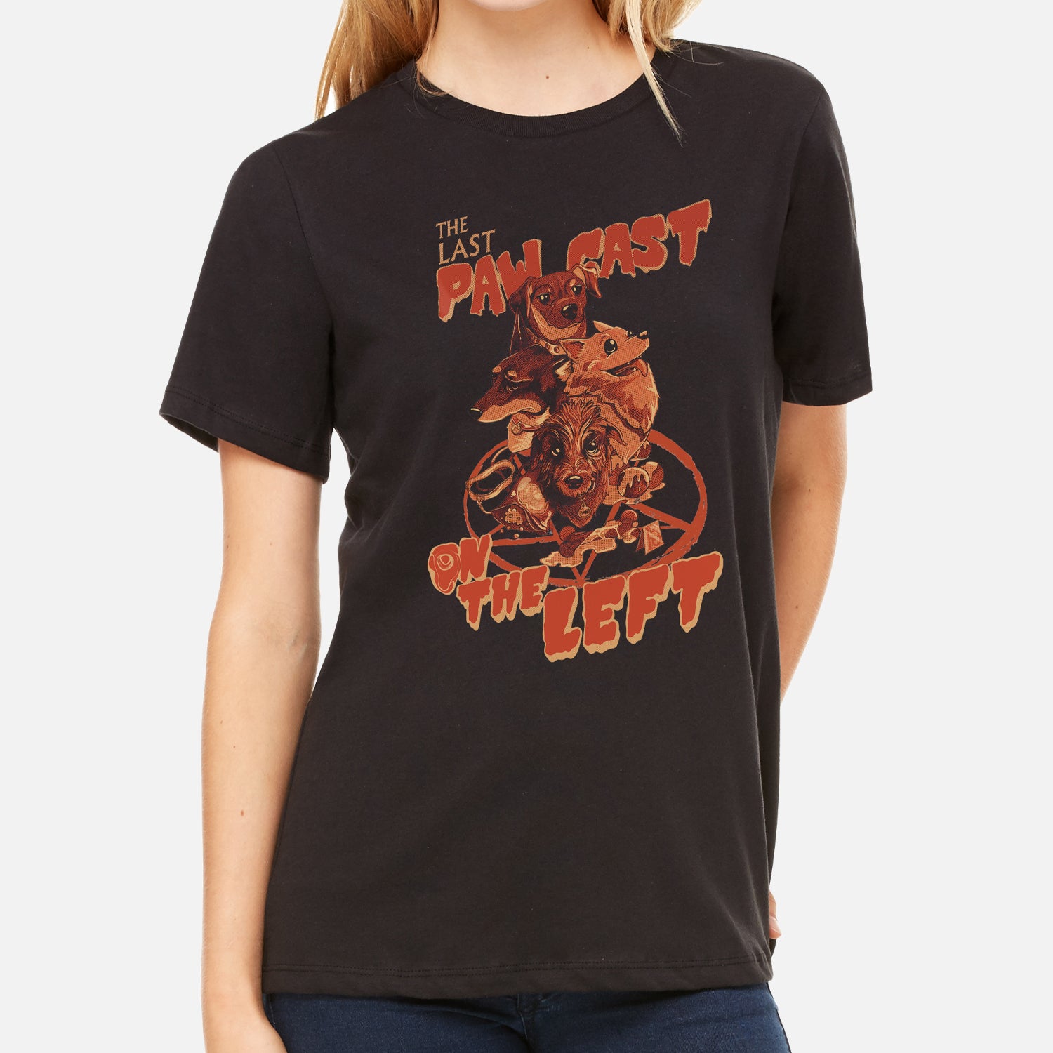 Woman in black shirt with orange graphic featuring dogs and pentagram with text "THE LAST PAW CAST ON THE LEFT"