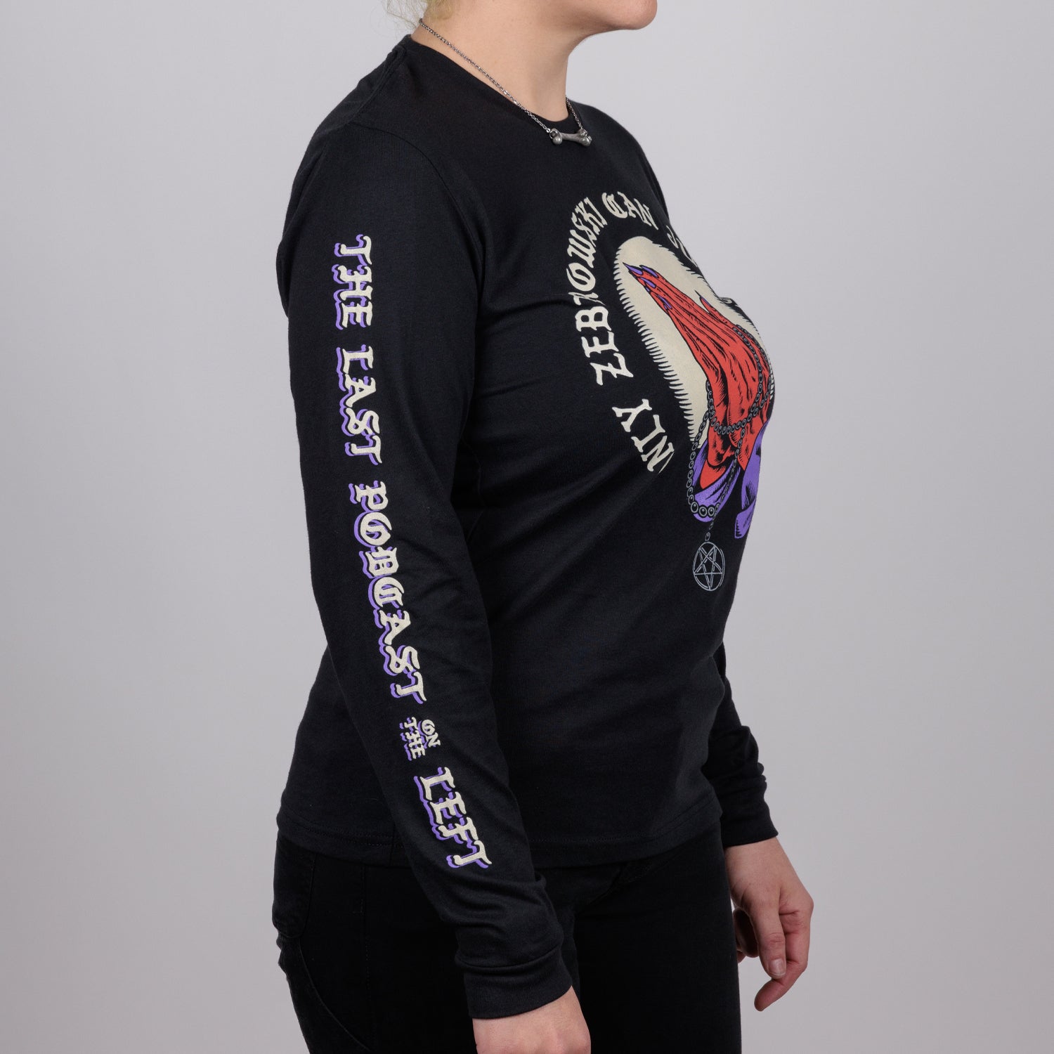 side view of Woman in black shirt with praying hands graphic surrounded by text "ONLY ZEBROWSKI CAN JUDGE ME" and text on right sleeve "THE LAST PODCAST ON THE LEFT"