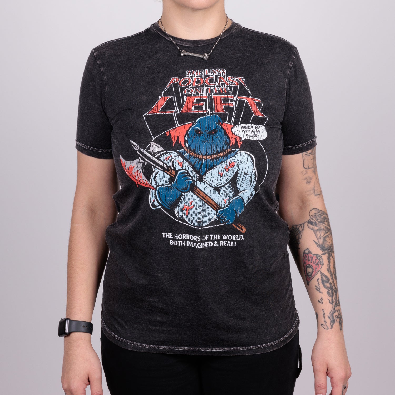 Woman in Vintage-Washed Executioner Tee, black tee with graphic of excecutioner with text "THE LAST PODCAST ON THE LEFT" and text below graphic "THE HORRORS OF THE WORLD BOTH IMAGINED AND REAL!"